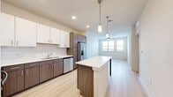 Located at 707 W Slaughter Lane in Austin, TX 78748, this one-bedroom, one-bathroom unit offers a thoughtfully designed single-floor layout with a clean, contemporary aesthetic throughout. Light wood-style flooring flows seamlessly across the entire space, creating a bright and cohesive feel.

The kitchen is a standout feature, showcasing a two-tone cabinetry design with white upper cabinets and wood-finish lower cabinets, complemented by white subway tile backsplash and light quartz countertops. Stainless steel appliances — including a range, microwave, and dishwasher — add a modern touch, while a peninsula with additional cabinetry provides extra prep and storage space. Pendant lighting above the peninsula and recessed ceiling lights complete the polished look.

The bedroom is a comfortable, well-lit space featuring a ceiling fan, a window with natural light and outdoor views, and clean white walls that enhance the airy atmosphere.

The bathroom continues the wood-finish cabinetry theme, offering a full vanity with ample storage, a soaking tub with shower, and light flooring consistent with the rest of the unit. A dedicated walk-in closet is conveniently accessible directly from the bathroom, providing practical and well-organized storage. The overall ambiance is modern, neutral, and move-in ready.