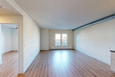 This single-floor unit offers a clean, modern aesthetic with an open-concept design that seamlessly connects the living and kitchen areas. Light wood-tone flooring flows consistently throughout the space, lending warmth and continuity across every room. A standout architectural detail is the exposed metallic ductwork that runs prominently through the main living area, giving the space an industrial loft character.

The kitchen is well-appointed with light wood cabinetry, dark countertops, stainless steel appliances including a full-size refrigerator and dishwasher, and a built-in sink. Track lighting above the kitchen adds functional illumination. The open living area benefits from large windows that invite generous natural light and offer views of the surrounding neighborhood, complemented by a baseboard heating unit beneath the sill.

The bedroom areas feature stylish muted-tone doors, clean white walls, and open closet shelving for practical storage. The bathroom is finished with light wood cabinetry, a white vanity countertop, wood-tone flooring, and a bathtub-shower combination. Throughout the unit, the neutral color palette, consistent flooring, and modern fixtures combine to create a bright, functional, and contemporary living environment.
