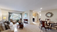 This thoughtfully designed one-bedroom, one-bathroom residence offers an efficient and comfortable single-floor layout. The open living and dining area serves as the heart of the home, featuring plush wall-to-wall carpeting and a large window dressed with elegant drapes and horizontal blinds that invite generous natural light. The living area provides ample space for relaxed seating and casual entertaining, while the adjacent dining space accommodates a full dining set, complete with wall art and decorative accents that lend warmth to the room.

The galley-style kitchen is equipped with light wood cabinetry, a black electric range, a full-size refrigerator, and a window above the counter that brings in additional natural light. Light-toned flooring completes the clean, functional aesthetic.

The bedroom is a well-sized, carpeted retreat featuring soft, neutral tones and sufficient space for a queen bed and nightstands. A dedicated closet provides practical storage.

The bathroom is finished with white tile throughout, featuring a full tub-shower combination, a toilet, and a wood-toned vanity with an integrated sink. The overall ambiance of the residence is calm and neutral, with consistent warm tones, carpet flooring in living areas, and recessed lighting offering a welcoming, move-in ready environment.