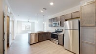 This well-appointed two-bedroom, two-bathroom residence in Greenville, SC offers a thoughtfully designed single-floor layout with a clean, modern aesthetic throughout. Light wood-style flooring flows through the main living areas and kitchen, creating a bright and cohesive feel. The kitchen is equipped with stainless steel appliances—including a refrigerator, range, and over-the-range microwave—complemented by rich dark-toned cabinetry, stone-look countertops, and crown molding accents. Both bedrooms feature plush carpet flooring, ceiling fans, and generous natural light from large windows. The primary bedroom connects to a well-sized bathroom with a dark wood vanity, granite-style countertop, and a spacious walk-in closet with built-in shelving and hanging rods. The second bathroom mirrors the same refined design, featuring additional wall-mounted cabinetry for storage. A dedicated laundry area houses a full-size washer and dryer. The entry foyer offers a welcoming transition into the living space, with neutral wall tones and crown molding lending a polished finish. This residence combines practical amenities with modern design details for comfortable everyday living.
