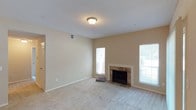 This single-floor, 2-bedroom, 2-bathroom residence offers a well-appointed layout designed for comfortable everyday living. The living area serves as the heart of the home, featuring a classic tile-surround fireplace with a clean white mantle that adds warmth and character to the space. Plush wall-to-wall carpeting runs throughout, complementing the neutral, warm-toned walls that create a welcoming ambiance. Multiple windows allow generous natural light to fill the room, enhancing the open and airy feel of the interior. A textured ceiling adds subtle architectural detail overhead, while flush-mount lighting provides consistent illumination. Visible HVAC venting integrated into the walls ensures year-round climate comfort. The living space flows naturally toward additional rooms, offering a functional and connected floor plan. The two bedrooms provide private retreats, and the two full bathrooms add convenience for residents and guests alike. Overall, the space presents a clean, move-in-ready environment with classic finishes and practical design elements that cater to a broad range of lifestyles.