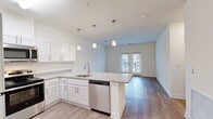 This single-floor residence in Mechanicsville, Virginia offers a well-organized layout comprising three bedrooms, two bathrooms, a kitchen, living room, laundry room, hallway, and closet. The open-concept kitchen and living area serves as the heart of the home, anchored by a peninsula island with granite countertops, white shaker cabinetry, pendant lighting, and stainless steel appliances including a dishwasher, refrigerator, microwave, and range. Wood-style flooring flows throughout the main living areas, lending a cohesive, contemporary look. French doors at the end of the living room allow natural light to filter in and provide views of the surrounding neighborhood. The primary bedroom features plush carpeting and connects to a private bathroom with a double-sink vanity topped with granite countertops, a large mirror, and wood-style flooring. The secondary bedrooms are also carpeted and receive natural light through windows with exterior views. The second bathroom includes a full tub-shower combination and wood-style flooring. A dedicated laundry room accommodates a full-sized washer and dryer side by side, adding everyday convenience to this efficiently designed residence.