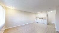 This studio in El Paso, TX offers a well-organized, single-floor layout that makes efficient use of its space. The open main area seamlessly combines the living and kitchen zones, creating a functional and cohesive environment. The kitchen is equipped with white cabinetry, a granite-style countertop, a white range with overhead microwave, and a full-size refrigerator — providing all essential appliances in a clean, compact arrangement. A textured block-style accent wall adds a subtle architectural detail to the living area, complemented by light wood-look flooring that runs throughout the unit for a clean, modern aesthetic. A large window fitted with vertical blinds allows natural light to fill the space, while a wall-mounted air conditioning unit ensures climate control. The textured ceiling adds a classic finishing touch overhead. The bathroom features a white vanity and a shower/tub combination, accessible through a paneled door. A dedicated closet provides practical storage. The neutral color palette throughout — soft beiges and crisp whites — creates a bright, airy atmosphere that is easy to personalize. This studio is a straightforward and functional space suited for those seeking simplicity in El Paso's west side.