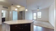 Located at 2300 E Alberta Rd in Edinburg, Texas, this single-floor unit offers a well-designed, open layout that efficiently connects the main living spaces. The kitchen is a standout feature, showcasing rich dark cabinetry that extends to the upper walls, light stone-look countertops, and a full suite of black appliances including a refrigerator, range, microwave, and dishwasher. A central island with matching countertop provides additional prep space and casual seating, while pendant lighting above and a built-in desk nook nearby add both style and function. Wood-look flooring runs throughout the kitchen and main living areas, creating a warm, cohesive aesthetic. The living room is bright and welcoming, anchored by a ceiling fan and a glass-paned door that brings in natural light and provides access to the exterior. A dedicated laundry closet with hookups is conveniently located off the main hall. The bedroom is generously sized, fitted with plush carpet and a ceiling fan, and connects directly to the bathroom, which features dark vanity cabinetry, a tub-shower combination with tiled surround, and wood-look tile flooring. Louvered closet doors and ample storage throughout round out this practical and comfortable living space.
