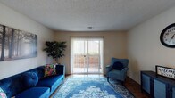 This single-floor, 2-bedroom, 1-bathroom residence in Memphis, Tennessee offers a well-organized layout designed for comfortable everyday living. The living room serves as the heart of the home, featuring hardwood-style flooring, a textured ceiling, and a large sliding glass door with vertical blinds that opens to a private balcony, filling the space with natural light and providing outdoor access. Adjacent to the living area, the kitchen and dining area are thoughtfully connected, with the kitchen showcasing white cabinetry, a dishwasher, and ample counter space. The dining area features matching hardwood-style flooring and a louvered closet door, providing convenient storage. The primary bedroom is carpeted and bright, with a window that invites natural light. The second bedroom, also carpeted, features a distinctive two-toned gray and neutral striped accent wall and a window overlooking the outdoors. The shared bathroom is clean and practical, with a white vanity, under-sink storage, and a mirror with a medicine cabinet. A standout feature of this residence is the in-unit laundry area, accommodating a full-size washer and dryer behind a louvered door — a practical convenience. Throughout the home, louvered closet doors, neutral tones, and hardwood-style and carpet flooring create a cohesive, functional living environment.