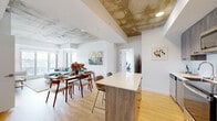 Located at 30 Rue Jos-Montferrand in Gatineau, this modern one-bedroom, two-bathroom unit offers a well-planned open-concept layout with contemporary design elements throughout. The space is defined by striking exposed concrete ceilings that lend an industrial character, complemented by light hardwood flooring and crisp white walls.

The kitchen is outfitted with stainless steel appliances, including a French-door refrigerator, electric range, built-in microwave, and dishwasher. Textured grey wood cabinetry pairs with white countertops, and a kitchen island with bar seating connects seamlessly to the dining and living areas.

The living room benefits from large floor-to-ceiling windows that bring in generous natural light and frame views of the surrounding Gatineau cityscape. The bedroom is a comfortable retreat featuring a spacious sliding-door closet and its own large window overlooking the city skyline.

Two well-appointed bathrooms serve the unit: one features a tiled walk-in glass shower with a floating vanity, while the second includes a full soaking tub with tiled surround and a wood-toned vanity with a white countertop. Throughout, the clean, modern finishes create a cohesive and polished ambiance.