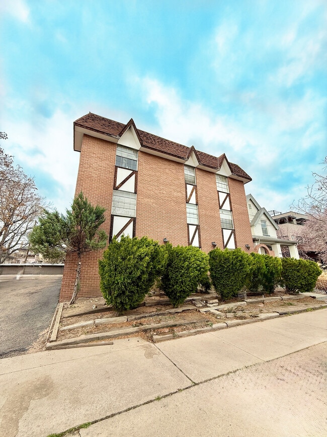 Charming brick apartment building with unique architectural details and lush greenery, set against a vibrant blue sky. - Washington Plaza