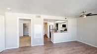 This single-floor residence offers a thoughtfully designed open-concept layout that connects the living, dining, and kitchen areas seamlessly. The living room is bright and welcoming, featuring wood-look laminate flooring, a ceiling fan, and multiple windows fitted with horizontal blinds that invite natural light while framing outdoor views. A private door provides direct access to an exterior space, enhancing the indoor-outdoor flow.

The kitchen is a functional highlight of the space, outfitted with stainless steel appliances including a refrigerator, range, over-the-range microwave, and dishwasher. Crisp white cabinetry, subway tile backsplash, and light-toned countertops contribute to a clean, modern aesthetic. A peninsula with a built-in sink adds counter space and creates a natural division between the kitchen and living area.

The bedroom is carpeted for comfort and features a spacious sliding-door closet with built-in shelving and hanging rods. A walk-in closet is also visible from the main living area, offering generous storage capacity. The bathroom is well-appointed with a vessel-style sink, wood-look vanity countertop, a large mirror, and a full tub-shower combination. Wood-look flooring carries through the bathroom, tying the space together with a cohesive design. Neutral wall tones and textured ceilings complete the overall aesthetic throughout.