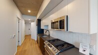 Located in the heart of Portland's vibrant West End neighborhood, this modern unit at 1510 SW Alder offers a thoughtfully designed single-floor layout with contemporary finishes throughout. The open living area flows seamlessly into the galley-style kitchen, which is equipped with stainless steel appliances including a gas range, over-the-range microwave, dishwasher, and refrigerator. Sleek dark lower cabinetry is paired with crisp white upper cabinets, complemented by a white subway tile backsplash and dark quartz countertops with a matte black sink fixture — creating a striking, modern aesthetic. Exposed concrete ceilings lend an industrial character to the space, while light wood-tone flooring runs throughout, adding warmth and continuity. The bedroom features large floor-to-ceiling windows that frame sweeping views of the Portland cityscape, filling the room with natural light. The bathroom is finished with marble-look tile in the tub and shower surround, matte black fixtures, a dark vanity with quartz countertop, and a large mirror, offering a clean and refined look. The overall design balances urban industrial elements with modern comfort, making for a stylish and functional living space in one of Portland's most walkable neighborhoods.