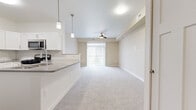 Located at 11629 E Gemstone Ln in Wichita, KS, this well-designed single-floor unit offers a thoughtful layout with a bright, open-concept living space. The kitchen is a standout feature, showcasing white shaker-style cabinetry, a classic subway tile backsplash, gray quartz countertops, and a full suite of stainless steel appliances including a gas range, microwave, and refrigerator. A peninsula with pendant lighting provides additional prep space and connects seamlessly to the living area, which features plush carpeting and a ceiling fan. Sliding glass doors flood the living room with natural light and open to a private balcony with views of the surrounding community. The unit also includes a dedicated laundry area and a walk-in pantry or storage closet adjacent to the kitchen. Wood-look flooring runs through the kitchen and bathroom, while plush carpet adds warmth to the bedroom and living spaces. The bedroom is well-proportioned, featuring a window with blinds and ample wall space. The bathroom is clean and functional, finished with wood-look flooring, a white vanity with gray countertops, and chrome accents. A programmable thermostat and multiple HVAC vents ensure year-round comfort throughout the unit.