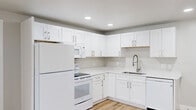 This single-floor, 2-bedroom, 2-bathroom residence offers a thoughtfully laid-out interior finished with consistent, modern details throughout. Light wood-tone flooring runs continuously across all rooms, complementing the neutral gray-and-white color palette that gives the space a clean, bright feel.

The kitchen is a standout feature, outfitted with crisp white shaker-style cabinetry, white quartz countertops, and brushed nickel hardware. White appliances — including a refrigerator, range, microwave, and dishwasher — are neatly integrated, and a recessed ceiling with can lighting adds a polished touch. The kitchen opens toward the main living area, creating an efficient and connected layout.

Both bedrooms are well-proportioned, each featuring recessed lighting, wall-mounted air conditioning units, and windows that allow natural light to filter in. The primary bedroom offers a generous footprint with direct access to a closet. A central hallway connects the bedrooms to the rest of the unit, lined with clean white panel doors and additional closet storage.

The bathrooms are finished with white shaker vanities, quartz countertops, undermount sinks, and brushed nickel fixtures. One bathroom includes a tub and shower combination enclosed by sliding glass doors with white subway tile surround. Recessed lighting and large mirrors enhance both bathrooms' bright, functional design.