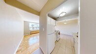 Located at 1275 Danforth Rd in Toronto's Scarborough neighbourhood, this 2-bedroom, 1-bathroom unit offers a practical and well-laid-out single-floor living space. Warm-toned parquet flooring runs throughout the living areas and both bedrooms, lending a classic character to the interior. Neutral beige walls and white trim create a clean, cohesive aesthetic across all rooms.

The spacious living room receives generous natural light through a large window, complemented by a radiator that provides efficient heating. Both bedrooms are comfortably sized, each featuring double-door closets for ample storage. The primary bedroom benefits from a bright window with views of the surrounding neighbourhood. The second bedroom mirrors this layout, also equipped with a built-in closet.

The galley-style kitchen is efficiently designed with white cabinetry lining both walls, light granite-effect countertops, a double sink, subway tile backsplash, and white appliances including an electric range and refrigerator. Light ceramic tile flooring completes the kitchen's clean look.

The bathroom features crisp white subway tile surrounding a full bathtub and shower, a white vanity with medicine cabinet, maintaining a bright and functional finish throughout. A connecting hallway ties all rooms together in a logical and accessible floor plan.
