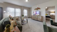 This single-story residence in Oklahoma City, OK, offers a thoughtfully designed open-concept floor plan that connects the main living spaces seamlessly. The living room is generously proportioned, featuring plush carpeting, multiple windows with sheer curtains that invite abundant natural light, and ample space for comfortable furnishings. It flows naturally into a dedicated dining area, which benefits from a bright corner window arrangement offering pleasant outdoor views.

The kitchen is a standout feature, equipped with rich dark cabinetry extending to the upper walls, stainless steel appliances, a tile backsplash, and a large central island topped with striking marble-style countertops. Wood-look tile flooring adds warmth and practicality to this space, which also includes a breakfast bar with seating.

The residence includes two well-sized bedrooms, each carpeted and outfitted with ceiling fans and windows providing natural light. Both rooms offer comfortable proportions suited to full bedroom furniture sets.

The bathrooms continue the design consistency of the home, featuring dark vanity cabinetry, marble-style countertops, tile flooring, and well-lit vanity mirrors. One bathroom includes a tub-shower combination, while additional closet and laundry access is conveniently integrated nearby, completing this functional and attractive layout.