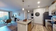 Located at 100 Flint Pond Cir in Shrewsbury, Massachusetts, this single-floor residence offers a thoughtfully designed open-concept layout with contemporary finishes throughout. The kitchen serves as the heart of the home, anchored by a granite-topped island with a stainless steel undermount sink and pendant lighting above. Stainless steel appliances, including a refrigerator and dishwasher, complement the white cabinetry, while a stacked in-unit washer and dryer add convenient functionality just steps away. Durable wood-style flooring flows throughout the main living areas, transitioning seamlessly from the kitchen into the dining and living spaces. The living room is bright and inviting, featuring large sliding glass doors that open to a private balcony with outdoor views, allowing ample natural light to fill the room. Two well-proportioned bedrooms provide comfortable retreats, each with plush carpeting and generously sized windows. The bathroom is finished with granite countertops, shaker-style cabinetry, a combined soaking tub and shower, and a large mirror with overhead lighting. Throughout the residence, neutral gray tones create a calm, cohesive ambiance, while recessed lighting and modern fixtures add a polished, contemporary feel to every room.