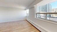 This 360 square foot studio apartment, located in Toronto, offers a compact yet functional living space. The unit features an open-concept design, maximizing the use of limited square footage. Light wood laminate flooring runs throughout, creating a warm and inviting atmosphere.

The main living area is bright and airy, benefiting from large windows that provide ample natural light and stunning views of the surrounding cityscape. A baseboard heating system ensures comfort year-round.

The bathroom showcases a modern design with clean lines. White subway tiles adorn the walls of the shower area, complementing the overall minimalist aesthetic of the space.

The kitchen, while not visible in the images, is likely integrated into the main living area, maintaining the open feel of the studio. A partial wall suggests a thoughtful division of space, potentially separating the sleeping area from the main living zone.

Storage appears to be efficiently incorporated, with a closet visible in one of the images. The neutral color palette, dominated by whites and light tones, enhances the sense of spaciousness.

This studio apartment, situated in a high-rise building, offers a perfect blend of functionality and style for urban living. Its layout and features make it an ideal choice for young professionals or students seeking a modern, low-maintenance home in the heart of Toronto.