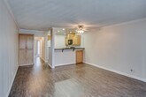 Located at 2828 W Ball Rd in Anaheim, California, this single-floor unit offers a well-organized layout with a comfortable, functional design throughout. The open-concept living and dining area is finished with warm hardwood-style flooring and accented by crown molding along the ceiling. A ceiling fan with a light fixture provides both comfort and illumination, while a large sliding glass door fitted with vertical blinds allows abundant natural light to fill the space.

The kitchen is defined by a raised peninsula that serves as a natural divider between the living area and the cooking space. Light wood cabinetry pairs with dark granite countertops, and black appliances — including a range and over-the-range microwave — complete the kitchen's cohesive aesthetic. Recessed lighting overhead adds a polished touch.

The bedrooms feature plush wall-to-wall carpeting, ceiling fans, and vertical blind-covered sliding doors or windows that bring in ample natural light, creating a calm and restful atmosphere. The bathroom is well-appointed with a tub and shower combination enclosed by sliding glass doors, a wood-toned vanity topped with dark granite, and a neutral color palette that ties the space together cleanly. Overall, the unit presents a practical and inviting living environment in a convenient Anaheim location.