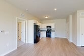 Located at 151 S Davis Rd in LaGrange, Georgia, this single-story, one-bedroom, one-bathroom unit offers a practical and modern living experience. The open-concept layout seamlessly connects the kitchen, dining, and living areas into one cohesive space. The kitchen is well-equipped with white shaker-style cabinetry, dark granite-look countertops, and a full suite of black appliances including a refrigerator, dishwasher, gas range, and over-the-range microwave. Light wood-look luxury vinyl plank flooring runs throughout the main living areas, lending a clean and contemporary feel. The living and dining area is bright and airy, featuring large windows that bring in natural light and offer outdoor greenery views, complemented by a ceiling fan overhead. The bedroom is a comfortable size, finished with plush carpet, a ceiling fan, and windows that frame pleasant outdoor views. A dedicated utility room houses a full-size front-loading washer and dryer. The bathroom features wood-look flooring, a full tub-shower combination, and a vanity with dark countertops. A closet provides additional storage. The overall design is clean, neutral, and move-in ready.