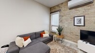 Located at 123 King Street in downtown London, Ontario, this well-appointed one-bedroom, one-bathroom unit offers a smart and efficient layout across a single floor. The living room is a welcoming space anchored by a charming exposed brick accent wall, light wood-look flooring, and a window that invites natural light. A wall-mounted mini-split unit provides climate control, complementing the room's clean, modern aesthetic. The kitchen is a functional highlight, featuring a U-shaped layout with light wood cabinetry, bold veined stone-look countertops, stainless steel appliances including a built-in microwave and electric range, and a double undermount sink — offering ample workspace and storage. The bedroom carries the same exposed brick character, with two windows that bring in natural light, and includes a full-width mirrored sliding closet with upper cabinetry, maximizing storage without sacrificing style. The bathroom is a neat, elongated space finished in light tile, featuring a vanity with cabinetry, a toilet, and a shower with sliding glass doors. The hallway entry is bright and practical, with upper storage cabinetry and light flooring that flows cohesively throughout the unit, creating a unified and polished feel.