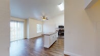 Located at 20800 Lake Chabot Rd in Castro Valley, California, this single-floor residence offers a well-designed layout that balances comfort and functionality. The open-concept kitchen is a standout feature, outfitted with white cabinetry, granite-look countertops, stainless steel appliances including a gas range, microwave, and refrigerator, and a central island that provides additional prep and storage space. Rich hardwood-style flooring flows throughout the kitchen and dining area, complemented by vaulted ceilings and a ceiling fan that enhance the sense of openness and airflow. The adjacent dining nook benefits from natural light streaming through a window, creating a bright and welcoming atmosphere. The spacious living room impresses with soaring vaulted ceilings, a tiled fireplace as a focal point, and large sliding glass doors fitted with vertical blinds that invite an abundance of natural light and outdoor views. The bedrooms are carpeted for comfort, each featuring windows with tree-lined views and baseboard heating. The bathrooms are finished in crisp white, with one offering a full tub-shower combination, vanity with under-sink storage, and a large mirror. The overall ambiance is clean, bright, and move-in ready.
