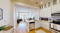 Located at 16408 Holly Crest Lane in Huntersville, NC, this well-appointed one-bedroom, three-bathroom residence offers a thoughtfully designed open-concept floor plan. The combined living, dining, and kitchen area serves as the heart of the home, where rich hardwood-style flooring flows seamlessly throughout. The kitchen is a standout feature, showcasing floor-to-ceiling white shaker cabinetry with glass-front upper panels, a subway tile backsplash, light quartz countertops, a spacious peninsula with bar seating, stainless steel appliances including a French door refrigerator, and elegant pendant lighting. The living room is bright and inviting, benefiting from a large set of French doors with transom windows above that open onto a private balcony, filling the space with natural light. The primary bedroom features plush carpet, a tray ceiling, and a generously sized walk-in shower clad in neutral large-format tile with a built-in bench and frameless glass enclosure. A stacked washer and dryer unit is conveniently housed in a dedicated laundry area. With three full bathrooms, a utility room, and a hallway connecting all spaces, this residence delivers a practical yet refined living experience in a compact and efficient footprint.