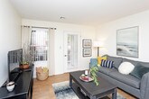 This single-floor residence offers a thoughtfully designed layout that balances comfort and functionality throughout. The living room serves as the heart of the home, featuring warm hardwood-style flooring, neutral walls, and a glass door that fills the space with natural light while providing access to the outdoors. The adjacent dining area flows seamlessly from the living room, accented by a decorative round mirror and framed artwork, creating an inviting atmosphere for everyday meals and entertaining. The galley-style kitchen is efficiently organized with white cabinetry, granite-style countertops, a double sink, and full appliance suite, with hardwood-style flooring continuing throughout. The primary bedroom is generously sized with plush carpeting, large windows fitted with vertical blinds for privacy, and ample natural light. It is complemented by a spacious walk-in closet with wire shelving for organized storage. The second bedroom also features soft carpeting and a bright window with sheer curtains. Both bathrooms are finished with granite-topped white vanities, tub-shower combinations, and hardwood-style flooring, offering a clean and cohesive aesthetic. Throughout the residence, the light color palette and consistent finishes create a calm, welcoming ambiance.