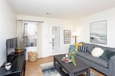 This single-floor residence offers a thoughtfully designed layout that balances comfort and functionality throughout. The living room serves as the heart of the home, featuring warm hardwood-style flooring, neutral walls, and a glass door that fills the space with natural light while providing access to the outdoors. The adjacent dining area flows seamlessly from the living room, accented by a decorative round mirror and framed artwork, creating an inviting atmosphere for everyday meals and entertaining. The galley-style kitchen is efficiently organized with white cabinetry, granite-style countertops, a double sink, and full appliance suite, with hardwood-style flooring continuing throughout. The primary bedroom is generously sized with plush carpeting, large windows fitted with vertical blinds for privacy, and ample natural light. It is complemented by a spacious walk-in closet with wire shelving for organized storage. The second bedroom also features soft carpeting and a bright window with sheer curtains. Both bathrooms are finished with granite-topped white vanities, tub-shower combinations, and hardwood-style flooring, offering a clean and cohesive aesthetic. Throughout the residence, the light color palette and consistent finishes create a calm, welcoming ambiance.