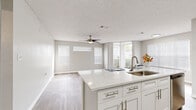 Located at 8801 Hunters Lake Dr in Tampa, FL, this single-floor residence offers a thoughtfully designed open-concept layout that maximizes every inch of its comfortable footprint. The living room is bright and airy, featuring light wood-look flooring, a ceiling fan, multiple windows with white blinds, and a sliding glass door that floods the space with natural light and provides outdoor access.

The kitchen flows seamlessly from the living area and is equipped with white shaker-style cabinetry, quartz countertops, a kitchen island with a single-basin sink, a white subway tile backsplash, and stainless steel appliances including a range and over-the-range microwave. Wood-look flooring continues through the kitchen, tying the open living and dining space together cohesively.

The bedroom is generously sized, finished with plush carpet, a ceiling fan, and a window for natural light. It includes direct access to both the full bathroom and a walk-in closet outfitted with wire shelving for ample storage. The bathroom features a white vanity with a quartz countertop, a tub/shower combo with white tile surround, and wood-look tile flooring. A dedicated laundry room with a full-size washer and dryer completes this practical and well-organized home.