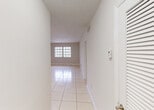 Located in Miami, FL, this single-floor residence offers a straightforward and functional layout with a bright, neutral aesthetic throughout. Light-colored large-format ceramic tile flooring spans every room, reflecting natural light and contributing to the open, airy feel of the interior.

The entry hallway leads into a spacious living area characterized by clean white walls, recessed ventilation, and generous windows that allow abundant natural light to filter in. The open flow between rooms enhances the sense of space across the floor plan.

The bedrooms are well-proportioned, each featuring ceiling fans with integrated lighting, large windows with vertical or bar-style blinds for privacy, and ample closet space. The neutral wall tones and tile flooring maintain a consistent, cohesive look throughout.

The bathroom is outfitted with mosaic tile on both the floor and tub surround, a full bathtub with shower, a white vanity, and a window that provides natural ventilation. A separate vanity area with dual mirrors and a built-in countertop offers additional grooming space.

The kitchen area, visible in the floor plan overview, is efficiently arranged with white cabinetry and a functional workspace. Throughout the home, clean lines, white trim, and an abundance of natural light create a calm and livable environment well-suited to Miami's sunny climate.