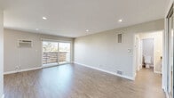 Located at 8501 S Sepulveda Blvd in Los Angeles, this thoughtfully designed one-bedroom, two-bathroom unit offers a bright and functional single-floor layout. The open-concept living and kitchen area is anchored by light wood-look flooring, neutral walls, and recessed lighting that creates a clean, modern atmosphere. Sliding glass doors lead to a private balcony, allowing natural light to fill the living space and offering outdoor views of the surrounding neighborhood.

The kitchen is well-appointed with white shaker cabinetry, dark countertops, a marble-style tile backsplash, stainless steel appliances including a dishwasher, and a peninsula that provides additional prep and serving space.

The bedroom features soft carpet flooring, a window with natural light and outdoor views, and a wall-mounted AC unit. A hallway lined with mirrored sliding closet doors connects to a well-designed bathroom featuring a long white vanity with ample cabinetry, stone countertops, and a mirrored medicine cabinet. A second bathroom includes a full tub-shower combination with clean white surround panels.

Throughout the unit, consistent finishes—white trim, neutral tones, and recessed lighting—contribute to a cohesive and contemporary aesthetic.