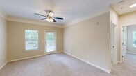 Located at 1200 Somerby Dr in Mobile, Alabama, this single-story, 3-bedroom, 1-bathroom home offers a well-designed layout across a comfortable footprint. The kitchen is a standout feature, boasting white cabinetry, granite countertops, stainless steel appliances including a range, microwave, and refrigerator, and durable wood-style flooring that adds a modern touch. It opens toward the living area, creating a functional flow throughout the common spaces. The spacious primary bedroom is generously sized, featuring plush carpeting, crown molding, a ceiling fan with light fixture, and a door providing direct access to an outdoor deck with views of surrounding greenery. The two additional bedrooms are well-proportioned with soft carpeting, ceiling fans, and large windows that invite natural light and outdoor views. The bathroom is clean and efficiently designed, featuring a full tub-shower combination with tiled surround and wood-style flooring. A dedicated laundry room houses a full-size washer and dryer with overhead shelving for added storage. Two closets and a hallway round out the layout, ensuring ample storage throughout. Warm neutral tones and consistent finishes lend the home a cohesive, inviting ambiance.