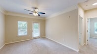Located at 1200 Somerby Dr in Mobile, Alabama, this single-story, 3-bedroom, 1-bathroom home offers a well-designed layout across a comfortable footprint. The kitchen is a standout feature, boasting white cabinetry, granite countertops, stainless steel appliances including a range, microwave, and refrigerator, and durable wood-style flooring that adds a modern touch. It opens toward the living area, creating a functional flow throughout the common spaces. The spacious primary bedroom is generously sized, featuring plush carpeting, crown molding, a ceiling fan with light fixture, and a door providing direct access to an outdoor deck with views of surrounding greenery. The two additional bedrooms are well-proportioned with soft carpeting, ceiling fans, and large windows that invite natural light and outdoor views. The bathroom is clean and efficiently designed, featuring a full tub-shower combination with tiled surround and wood-style flooring. A dedicated laundry room houses a full-size washer and dryer with overhead shelving for added storage. Two closets and a hallway round out the layout, ensuring ample storage throughout. Warm neutral tones and consistent finishes lend the home a cohesive, inviting ambiance.