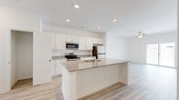 Located at 2108 Silty Soil Ct in Leland, NC, this two-story home offers a well-organized layout spread across two floors. The main level opens into a bright, open-concept kitchen and living area finished with light wood-look flooring and recessed lighting throughout. The kitchen is appointed with white shaker cabinetry, granite countertops, stainless steel appliances including a range, microwave, and refrigerator, and a central island with an undermount sink — ideal for both cooking and casual dining. A hallway connects the living area to additional rooms, including a convenient closet for pantry or storage use. The attached garage provides secure parking and additional storage space with an automatic opener. Upstairs, the two bedrooms are bright and airy, each featuring light wood-look flooring, ceiling fans, and windows that bring in natural light. The generously sized primary bedroom includes a walk-in closet with wire shelving. Three full bathrooms serve the home, each finished in a clean, neutral palette. With four closets total throughout the home, storage is plentiful. The clean, modern aesthetic and practical layout make this home a functional and comfortable residence in Leland, NC.