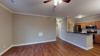 Located at 8913 Old Bardstown Rd in Louisville, Kentucky, this single-floor residence offers a thoughtfully designed layout with a cohesive blend of comfort and practicality. The living area is generously sized, showcasing rich hardwood flooring, crown molding, a ceiling fan with light fixture, and a sliding glass door fitted with vertical blinds that allows natural light to fill the space. The open-concept design connects the living area to the kitchen, which is equipped with stainless steel appliances including a refrigerator, electric range, and over-the-range microwave, complemented by warm wood cabinetry, dark countertops, and a dedicated pantry closet for added storage. An elegant chandelier illuminates the adjacent dining area, which also benefits from the same hardwood flooring and crown molding details. The bedrooms feature plush carpeting and ceiling fans, with one bedroom offering a window with exterior views and ample wall space. Additional rooms include a bathroom with a tub/shower combination, tile flooring, and a wood-vanity with a light countertop. The neutral gray-toned walls throughout the unit create a versatile backdrop, and a walk-in closet adds convenient storage. This residence offers a clean, move-in-ready environment with practical finishes throughout.