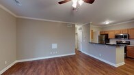 Located at 8913 Old Bardstown Rd in Louisville, Kentucky, this single-floor residence offers a thoughtfully designed layout with a cohesive blend of comfort and practicality. The living area is generously sized, showcasing rich hardwood flooring, crown molding, a ceiling fan with light fixture, and a sliding glass door fitted with vertical blinds that allows natural light to fill the space. The open-concept design connects the living area to the kitchen, which is equipped with stainless steel appliances including a refrigerator, electric range, and over-the-range microwave, complemented by warm wood cabinetry, dark countertops, and a dedicated pantry closet for added storage. An elegant chandelier illuminates the adjacent dining area, which also benefits from the same hardwood flooring and crown molding details. The bedrooms feature plush carpeting and ceiling fans, with one bedroom offering a window with exterior views and ample wall space. Additional rooms include a bathroom with a tub/shower combination, tile flooring, and a wood-vanity with a light countertop. The neutral gray-toned walls throughout the unit create a versatile backdrop, and a walk-in closet adds convenient storage. This residence offers a clean, move-in-ready environment with practical finishes throughout.