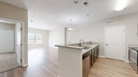 This contemporary apartment offers 930 square feet of thoughtfully designed living space. The layout includes two bedrooms, two full bathrooms, and an open-concept living and kitchen area. The primary bedroom, measuring 170 square feet, provides ample space for comfort.

The kitchen showcases modern appliances, including a stainless steel refrigerator and range. Taupe cabinetry contrasts nicely with light-colored countertops, creating a sleek aesthetic. A breakfast bar separates the kitchen from the living area, enhancing the open feel.

Throughout the apartment, neutral tones dominate, with light gray walls and white trim. Flooring varies, with durable vinyl plank in the main living areas and kitchen, and plush carpeting in the bedrooms. Large windows in the living room and bedrooms allow for plenty of natural light, creating a bright and airy atmosphere.

Both bathrooms feature updated fixtures, including vanities with ample storage and modern lighting. The in-unit laundry room, equipped with a washer and dryer, adds convenience to daily living.

The apartment's design prioritizes functionality and style, making efficient use of the available space while maintaining a modern, comfortable ambiance.