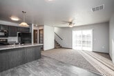 This two-story residence offers a thoughtfully designed layout across two levels. The main floor showcases an open-concept living and kitchen area, where wood-look hard flooring transitions seamlessly into plush carpeting in the living room. The kitchen is well-equipped with dark espresso cabinetry, a peninsula with a double sink and light countertops, pendant lighting, and a full suite of black appliances including a refrigerator, electric range, and over-the-range microwave. A dedicated entry door provides convenient access. The living area is bright and airy, benefiting from abundant natural light streaming through a large sliding glass door that opens to the outdoors. A ceiling fan adds both comfort and style, while a staircase leads to the upper level. A half bathroom on the main floor features tile flooring, a dark-cabinet vanity, and a large mirror. Upstairs, the carpeted bedrooms are generously sized with ample natural light from standard windows. The upper-level full bathroom is finished with tile flooring, a dark-wood vanity with a light countertop, a large mirror, and a combination tub and shower. Textured ceilings are present throughout, adding a classic residential finish to the entire space.