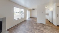 This single-floor unit offers a practical and well-organized layout designed for comfortable everyday living. The living area is generously sized, finished with wood-look vinyl plank flooring, and features a ceiling fan along with large windows and a sliding glass door that allow abundant natural light and outdoor views to fill the space. A pass-through opening connects the living area to the kitchen, enhancing the open flow between rooms.

The kitchen is efficiently designed in a U-shaped configuration, equipped with white cabinetry, grey countertops, and matching white appliances including an electric range, dishwasher, and refrigerator. A range hood and under-cabinet lighting add functional detail, while the wood-look flooring continues throughout for visual consistency.

The bedrooms are carpeted in a neutral beige tone and each includes a window offering outdoor views, contributing to a bright and comfortable atmosphere. The bathroom features wood-look flooring, a white vanity with grey countertop, and a separate enclosed water closet for added privacy. Overall, the unit presents a clean, neutral palette with updated finishes throughout, creating a move-in ready environment.