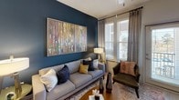 This single-story residence in Fort Mill, South Carolina, showcases a thoughtfully designed interior with modern finishes throughout. The open floor plan connects the living, dining, and kitchen areas seamlessly, creating a cohesive and functional flow.

The kitchen is a standout feature, equipped with dark wood-tone cabinetry, light granite countertops, stainless steel appliances including a full-size refrigerator, microwave, and dishwasher, and open display shelving. Light wood-style flooring runs underfoot, complementing the contemporary aesthetic. A generous island provides additional prep and dining space.

The living area features a bold navy accent wall, large windows that invite natural light, and ample room for comfortable furnishings. The bedroom continues the modern design with plush carpeting, a ceiling fan, natural light from well-dressed windows, and neutral toned walls offering a calm, restful atmosphere.

The bathroom is finished with light wood-style flooring, dark wood-tone vanity cabinetry topped with granite, a large mirror, and a tiled walk-in shower. Additional storage is accessible through multiple closet doors. The overall ambiance of the residence is contemporary, clean, and welcoming.