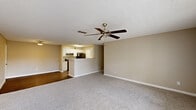This single-story, 3-bedroom, 2-bathroom home features a practical and cohesive layout designed for everyday comfort. The spacious living room is finished with plush carpeting, a ceiling fan with light fixture, and a textured ceiling, with large windows and a door providing natural light and outdoor access. It flows seamlessly into the combined dining and kitchen area, where white cabinetry, light countertops, a black electric range, and wood-look flooring create a clean, functional space with an open pass-through peninsula.

The three bedrooms are carpeted and finished with neutral tones, offering a calm atmosphere. The primary bedroom is generously sized and features a walk-in closet with wire shelving for organized storage. Additional bedrooms include double-door closets. Four total closets provide ample storage throughout the home.

Both bathrooms are appointed with white vanity cabinetry, light countertops, a tub-shower combination, and wood-look flooring, with well-lit vanity mirrors. A dedicated in-unit laundry room houses a full-size washer and dryer with overhead wire shelving. The home also includes a welcoming entrance and maintains a consistent, neutral color palette throughout.