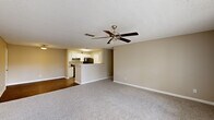 This single-story, 3-bedroom, 2-bathroom home features a practical and cohesive layout designed for everyday comfort. The spacious living room is finished with plush carpeting, a ceiling fan with light fixture, and a textured ceiling, with large windows and a door providing natural light and outdoor access. It flows seamlessly into the combined dining and kitchen area, where white cabinetry, light countertops, a black electric range, and wood-look flooring create a clean, functional space with an open pass-through peninsula.

The three bedrooms are carpeted and finished with neutral tones, offering a calm atmosphere. The primary bedroom is generously sized and features a walk-in closet with wire shelving for organized storage. Additional bedrooms include double-door closets. Four total closets provide ample storage throughout the home.

Both bathrooms are appointed with white vanity cabinetry, light countertops, a tub-shower combination, and wood-look flooring, with well-lit vanity mirrors. A dedicated in-unit laundry room houses a full-size washer and dryer with overhead wire shelving. The home also includes a welcoming entrance and maintains a consistent, neutral color palette throughout.