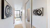Located on the sixth floor at 500 Upper Wellington Street in Hamilton, Ontario, this one-bedroom, one-bathroom unit offers a thoughtfully designed layout that maximizes every square foot of its compact footprint. The open-concept living area is a standout, anchored by dramatic floor-to-ceiling windows with sleek black frames that flood the space with natural light and provide sweeping views of the surrounding neighbourhood and treetops. Light hardwood-style flooring runs throughout, contributing to a bright, cohesive aesthetic.

The living room is clean and modern, with crisp white walls and generous wall space suited for artwork or media. The large glazed door provides access to a balcony, further enhancing the sense of openness.

The bedroom, though compact, features a neutral palette with white walls and light flooring, creating a calm and restful atmosphere. Its simple design allows for efficient furnishing.

The bathroom is finished to a contemporary standard, featuring large-format tile flooring, a combined tub and shower enclosed with dark marble-effect tile surround, a modern floating vanity with a light wood finish, and a large mirror with overhead lighting — all contributing to a clean, spa-like feel.

Overall, the unit presents a modern, minimalist character well-suited to urban living in Hamilton.