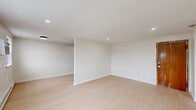 Located at 921 Tyson Ave in Philadelphia's 19111 zip code, this two-bedroom, one-bathroom unit offers a clean, modern interior across a single floor. The space is finished with light hardwood-style flooring throughout, lending a bright and cohesive feel to every room. Recessed lighting illuminates the open layout, complemented by crisp white walls and white baseboards that create a fresh, well-maintained aesthetic.

The generously sized primary bedroom is the standout space of the unit, offering ample room for furnishings and featuring multiple windows that bring in natural light, a window-mounted air conditioning unit, and baseboard heating. The second bedroom is compact yet functional, equipped with a built-in closet, a ceiling light fixture, and a window with exterior views. The unit also includes three closets in total, providing practical storage throughout.

The bathroom is tastefully updated with large-format white tile surrounding a soaking tub and shower combination, matte black fixtures and hardware, a wood-toned vanity, and a sleek mirror — offering a contemporary contrast to the otherwise neutral palette. The entry area provides a smooth transition into the main living space, reinforcing the unit's efficient and thoughtfully organized floor plan.