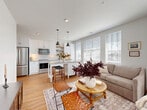 Located at 1350 W. 5th Ave in Columbus, OH, this well-appointed one-bedroom, one-bathroom residence offers a thoughtfully designed single-floor layout that maximizes both function and style. Warm hardwood-style flooring flows throughout, anchoring a clean, contemporary aesthetic defined by crisp white walls and modern black hardware accents.

The open-concept kitchen and living area serves as the heart of the home. The kitchen features white shaker cabinetry, stainless steel appliances including a French door refrigerator and range, a subway tile backsplash, quartz-style countertops, open wood shelving, and a central island with bar seating. The adjacent living area is bathed in natural light from large windows and offers a comfortable, versatile layout with space for a dining nook.

The bedroom is a serene retreat with generous windows dressed in elegant curtains, providing ample natural light. A dedicated office with glass-paneled doors and its own window offers a quiet, functional workspace. The full bathroom is well-proportioned with a white vanity, gray countertop, and access to a spacious walk-in closet. A hallway utility closet houses a stacked in-unit washer and dryer for added convenience. This residence combines modern finishes with practical living in a compact yet highly efficient floor plan.