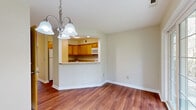 Located at 195 Van Rensselaer Blvd in Menands, NY, this single-floor residence offers three bedrooms and two bathrooms within a well-organized floor plan. Rich hardwood flooring runs throughout the main living and dining areas, while a hallway connects the living spaces to the bedrooms and bathrooms. The open-concept dining and living area is anchored by an elegant multi-light chandelier and features a pass-through opening to the kitchen, creating a connected and functional layout. The kitchen is equipped with warm-toned wood cabinetry, light granite countertops, a full suite of white appliances, and ample storage throughout. Natural light filters into the living area through large windows and a glass door leading to the outdoors. The bedrooms are carpeted for comfort, with neutral walls and generous closet space, including a full-width reach-in closet in at least one bedroom. The primary bedroom is a comfortable size, brightened by a large window with outdoor views. The bathrooms feature tile flooring and clean, functional fixtures, including grab bars for accessibility. The property also has a grassy yard area, visible from the exterior view, adding a sense of outdoor space to this practical and well-maintained Menands residence.