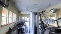 This fitness center offers a comprehensive workout environment designed to accommodate a variety of exercise routines. The space is outfitted with an extensive selection of strength-training machines, including cable systems, weight racks, and resistance equipment, providing users with options for both targeted muscle training and full-body workouts. Cardio machines are positioned toward the rear of the room, making efficient use of the available floor space.

The interior features a drop-panel ceiling equipped with multiple ceiling fans, which help maintain air circulation throughout the facility. The walls are lined with mirrors, enhancing the sense of openness and allowing users to monitor their form during exercise. Natural light filters in through windows along the perimeter, complementing the overhead lighting and contributing to a bright, functional atmosphere.

The flooring is designed to support heavy equipment and high-traffic use. The warm, neutral-toned walls create a clean and focused environment. Overall, the fitness center is thoughtfully arranged to maximize usability while maintaining an organized and accessible layout for all fitness levels.