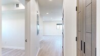 This thoughtfully designed one-bedroom, one-bathroom unit on the fifth floor of 1047 Fedora Street offers a clean, contemporary living experience in Los Angeles. Light-toned hardwood-style flooring runs throughout the space, complementing the crisp white walls and recessed lighting that create a bright, airy atmosphere.

The open living area is a standout feature, anchored by large black-framed sliding glass doors that lead to a private balcony, inviting abundant natural light and views of the surrounding cityscape. The kitchen is well-appointed with floor-to-ceiling wood-toned cabinetry, light countertops, stainless steel appliances including a refrigerator, over-the-range microwave, and electric range, all set against a clean white backsplash.

The bedroom is a calm retreat with light wood flooring, a window fitted with a roller shade, and dual wood-paneled doors — one leading to a closet and one to the hallway — outfitted with sleek matte black hardware. The bathroom features a modern aesthetic with herringbone-tiled walk-in shower enclosed by black-framed glass doors, mosaic tile flooring, a wall-mounted mirror with black detailing, and a wood-accented vanity. The entrance provides a welcoming transition into the rest of the unit, tying together the cohesive, modern design throughout.