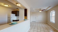 Located at 1602 Jacaman Rd in Laredo, Texas, this single-floor unit offers a well-organized layout designed for comfortable everyday living. Light-colored ceramic tile flooring runs consistently throughout the entire space, creating a cohesive and easy-to-maintain interior.

The open living and dining area is bright and airy, benefiting from natural light through a window fitted with blinds. A ceiling fan with a light fixture provides overhead comfort and airflow. A structural half-wall column partially separates this area from the kitchen, maintaining an open feel while defining each zone.

The kitchen features dark espresso-toned cabinetry that contrasts sharply with the light countertops and tile flooring. A double-basin sink sits beneath a pass-through window that looks into the living area, enhancing the sense of openness. The kitchen is equipped with a white electric range and ample upper and lower cabinet storage.

The unit includes two bedrooms, each with a ceiling fan and a closet — one featuring a walk-in style with built-in shelving rods. The bedrooms offer neutral wall tones and tile flooring, providing a clean and versatile canvas.

A full bathroom is present, finished with tile flooring and neutral walls. The textured ceilings are present throughout, and the overall layout is practical and efficiently designed for single-floor living in Laredo.