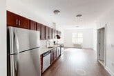 Located at 747 Grand Street in Jersey City, NJ, this well-appointed two-bedroom, two-bathroom residence offers a thoughtfully designed single-floor layout. The open-concept kitchen flows seamlessly into the living area, creating a bright and functional shared space. The kitchen is outfitted with rich mahogany-toned cabinetry, white subway tile backsplash, light countertops, and a full suite of stainless steel appliances including a refrigerator, electric range, dishwasher, and a modern gooseneck faucet with a stainless sink. Hardwood-style flooring runs throughout, lending warmth and continuity to the entire residence. The living area benefits from natural light through a window, complemented by a wall-mounted HVAC unit. Both bedrooms are clean and neutrally finished with white walls and ample natural light — the primary bedroom offers a comfortable footprint, while the second bedroom provides flexible utility. The two bathrooms are finished with classic white subway tile, featuring a tub-shower combination, a rich wood vanity with a white basin sink, and a large mirror. The overall aesthetic is clean, modern, and move-in ready, making this an ideal Jersey City residence.