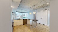 Located in the heart of downtown Grand Rapids at 15 Ottawa Ave NW, this modern 2-bedroom, 2-bathroom residence blends urban industrial design with contemporary finishes. Exposed concrete ceilings throughout lend an authentic loft-like character, while light hardwood flooring unifies the space with warmth and continuity.

The open-concept kitchen is a standout feature, equipped with stainless steel appliances including a refrigerator, range, and microwave, complemented by white cabinetry, a tile backsplash, and dark countertops. A peninsula with a built-in sink and breakfast bar seating is accented by stylish globe pendant lights, creating a functional yet inviting gathering space. Floor-to-ceiling windows flood the kitchen and living area with natural light and frame sweeping views of the Grand Rapids skyline.

The bedrooms are bright and well-proportioned, each featuring hardwood flooring and city views through large windows. The primary bedroom is accessed through a sleek sliding barn door with frosted glass panels, leading directly to its en-suite bathroom, which features a walk-in shower with full-height grey tile surround. The second bathroom offers a tub-shower combination with matching tile work. Two closets provide ample storage throughout the residence.