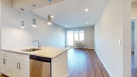 Located at 6804 Tides Rd in the Rockaway Beach neighborhood of Queens, New York, this single-floor unit offers a clean, modern design with a cohesive layout. Rich hardwood flooring runs throughout the living areas and bedrooms, contributing warmth and continuity across the space.

The open-concept living and kitchen area serves as the heart of the unit. The kitchen is outfitted with stainless steel appliances—including a refrigerator, range, and microwave—white shaker-style cabinetry, a tiled backsplash, and a peninsula with a light-toned countertop and an undermount sink. Cylindrical pendant lights hang above the peninsula, adding a contemporary touch. Recessed lighting illuminates the entire open area.

The living space flows naturally from the kitchen, benefiting from a window that introduces natural light and outdoor views. The bedrooms are well-proportioned, each featuring hardwood floors, neutral walls, large windows with exterior views, and individual PTAC wall units for climate control.

The bathroom is finished with large-format tile flooring, a white vanity with under-cabinet storage, a framed mirror, and a tiled shower enclosure with glass elements. The overall design is bright, neutral, and modern throughout.